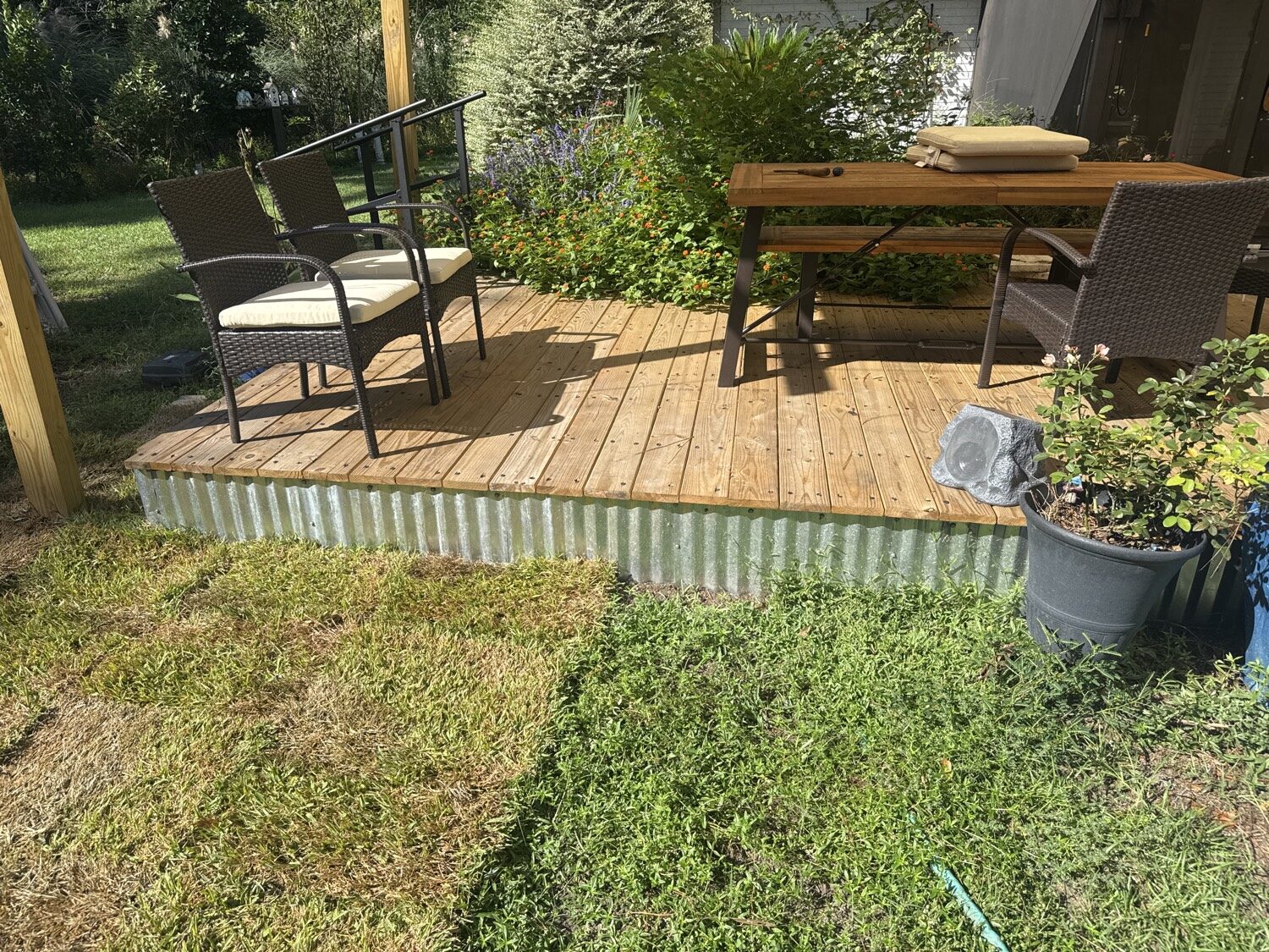 Finished PALLET-DEX deck with wood decking, chairs and table. Pallets are under the boards.
