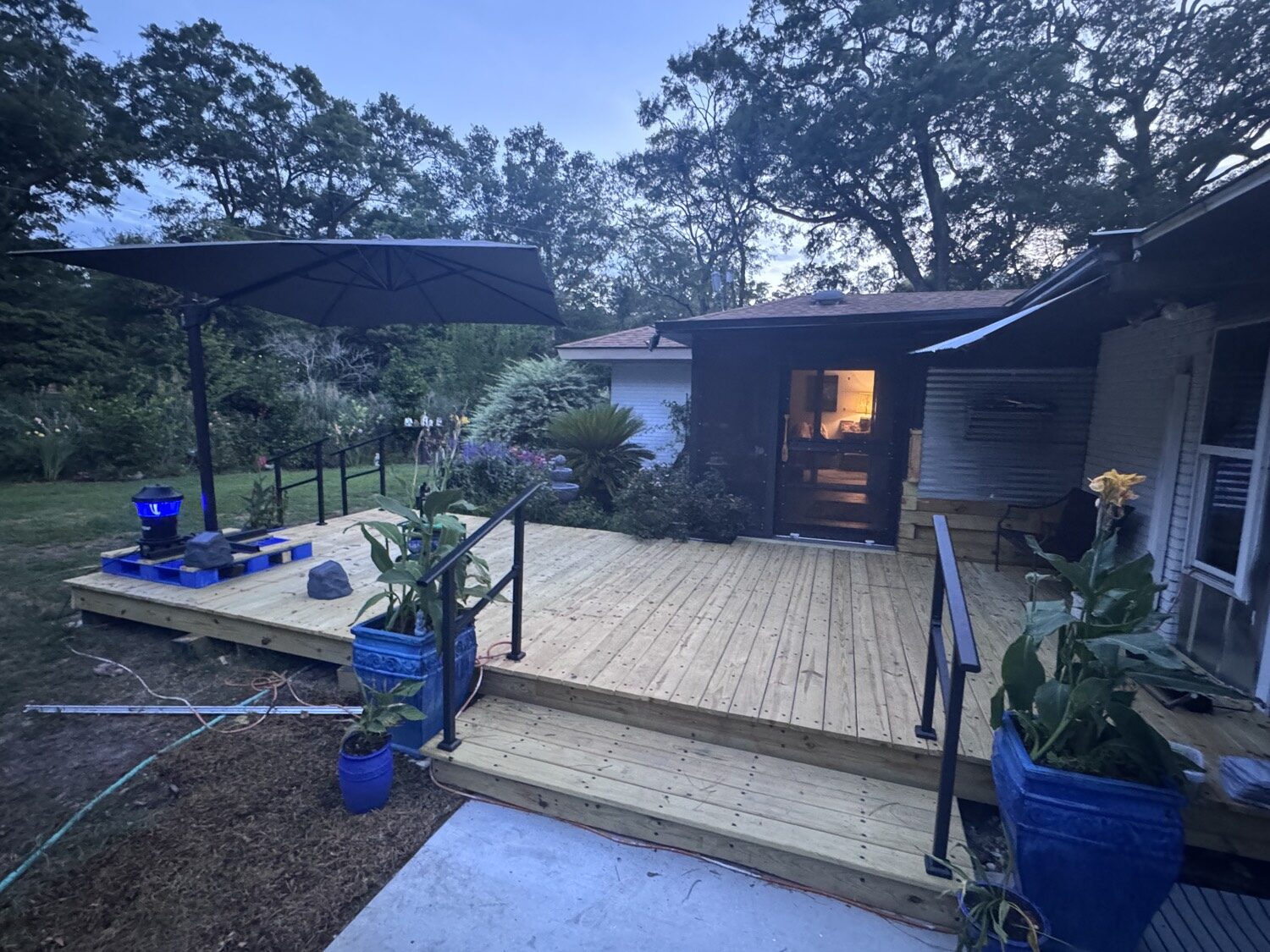 Finished PALLET-DEX deck at dusk with steps, rails, and umbrella.